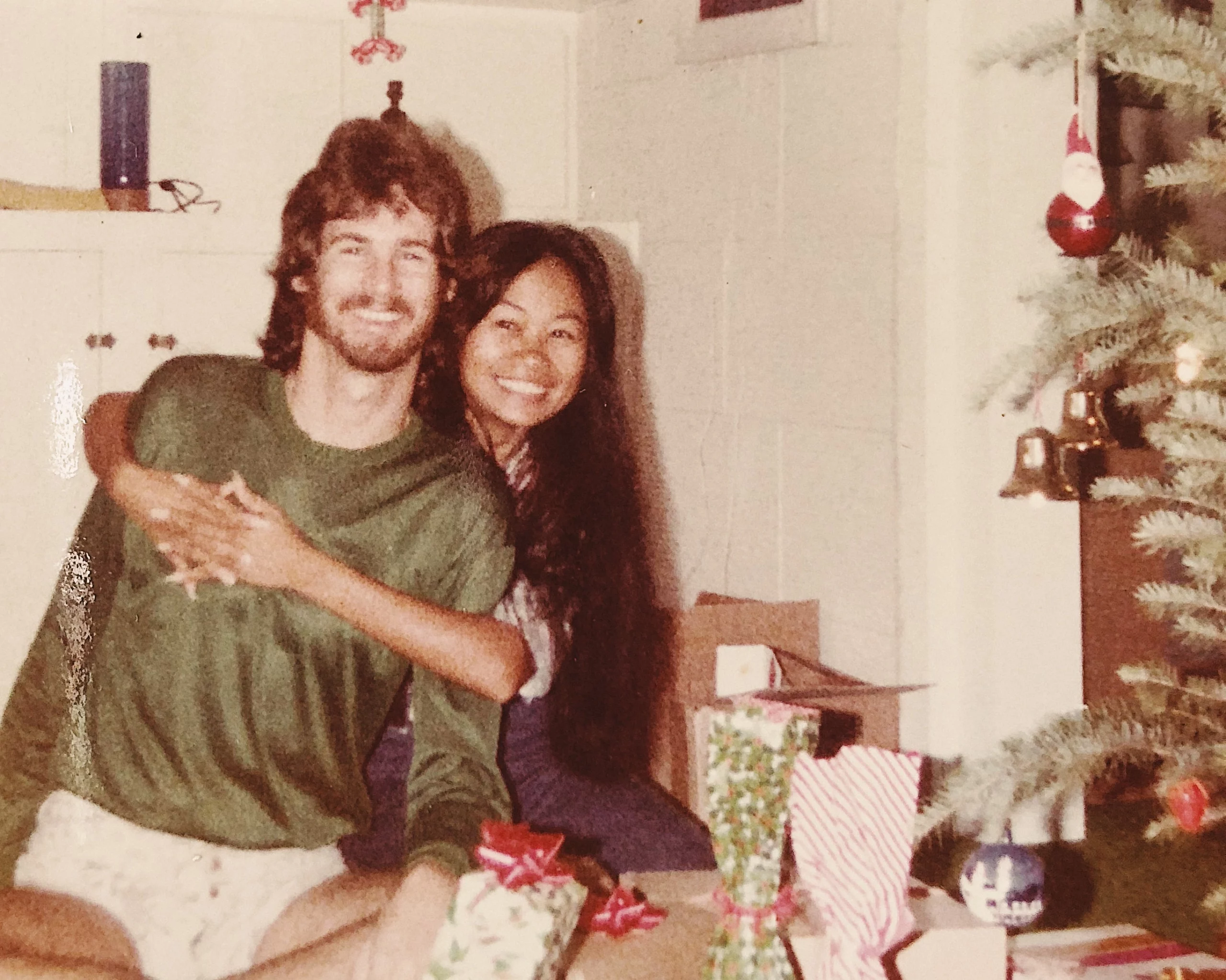 Phil Bennett crouching beside his young daughter outdoors, both smiling warmly, wearing a California beach t-shirt